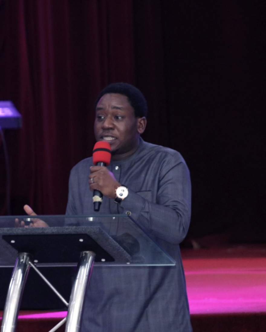 Tunde Adeniran speaking on stage at a podium